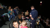 Policjant prowadzi pogadankę z dziećmi na temat bezpieczeństwa w kinie Helios w Szczecinie