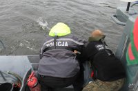 Funkcjonariusze Policji i Straży Granicznej podczas ćwiczeń ratownictwa wyciągają na pokład łodzi pozoranta znajdującego się w wodzie