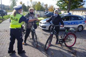 policjantka wręcza rowerzystom ulotki profilaktyczne