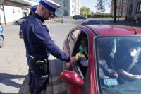 policjant rozdaje ulotki osobom w aucie
